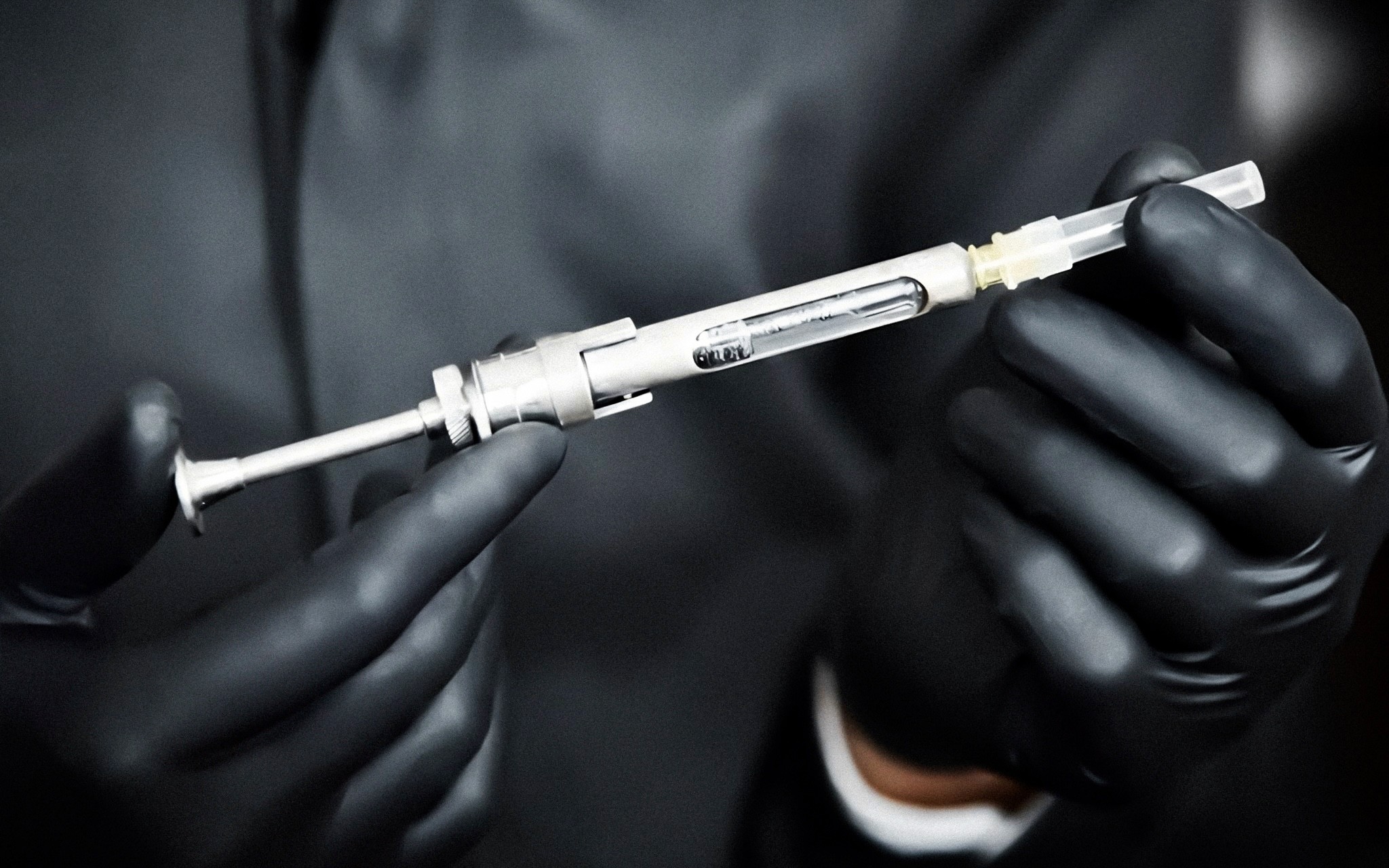 Close-up of Kristian Vendler's gloved hands holding a tattoo machine