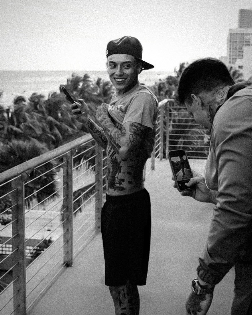 Black and white candid of Central Cee on a Miami balcony showing his tattoos