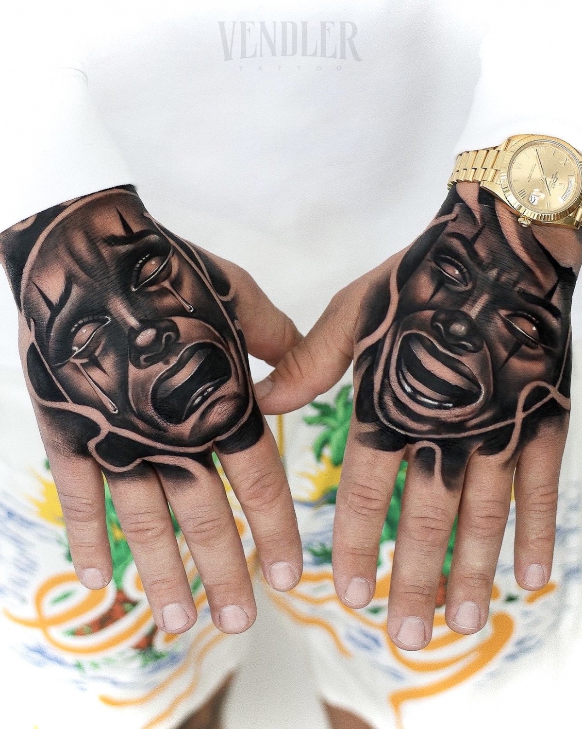 Matching smile-now-cry-later clown face tattoos on both hands