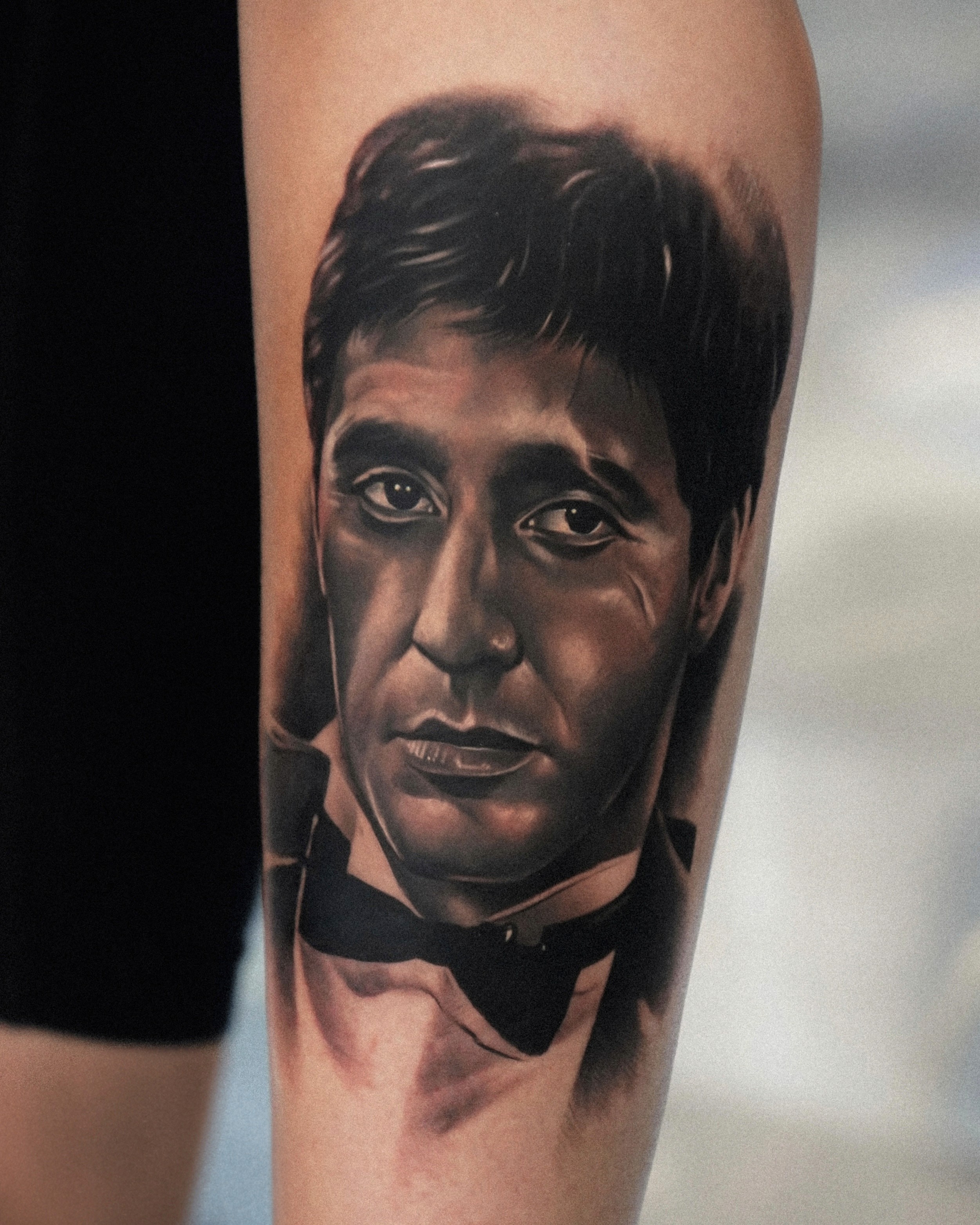 Black and grey realism forearm tattoo of Tony Montana in a tuxedo